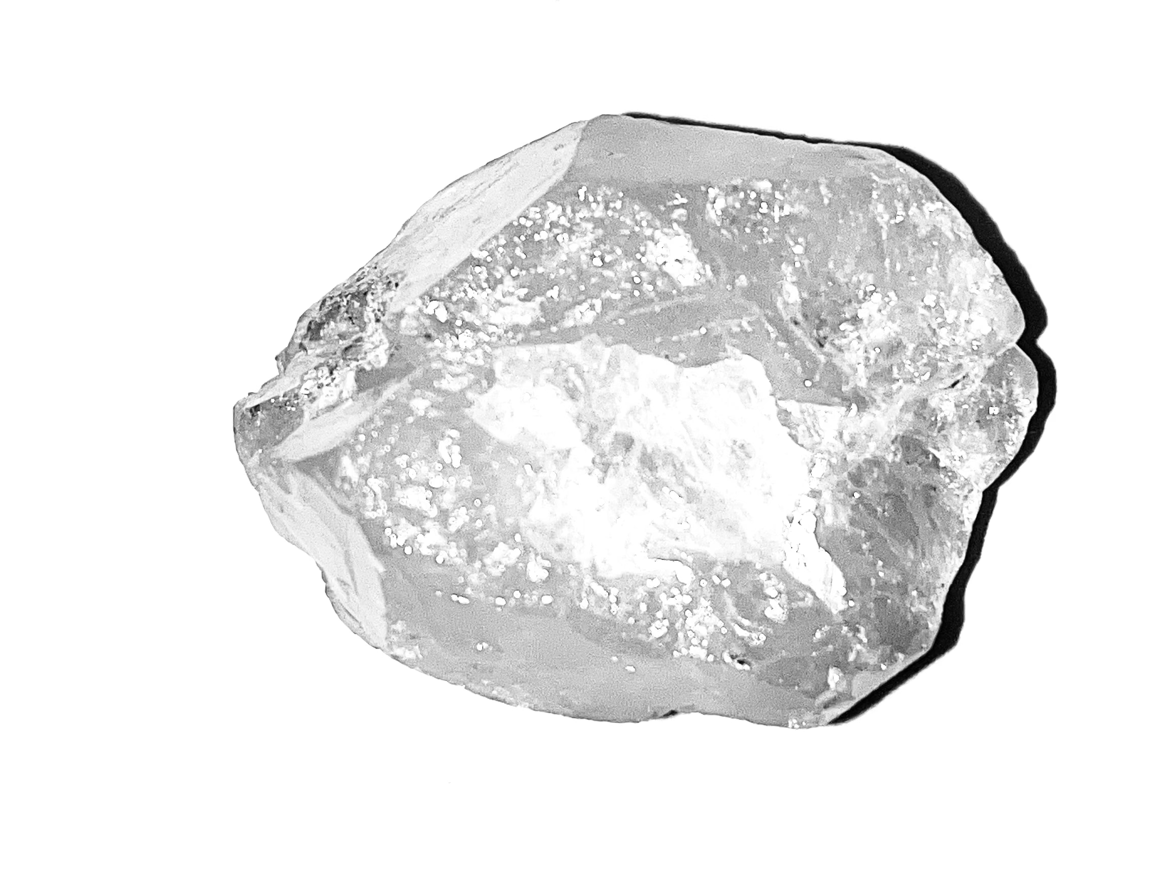 A rough, uncut clear gemstone with natural crystalline texture and sharp edges, photographed against a plain white background.