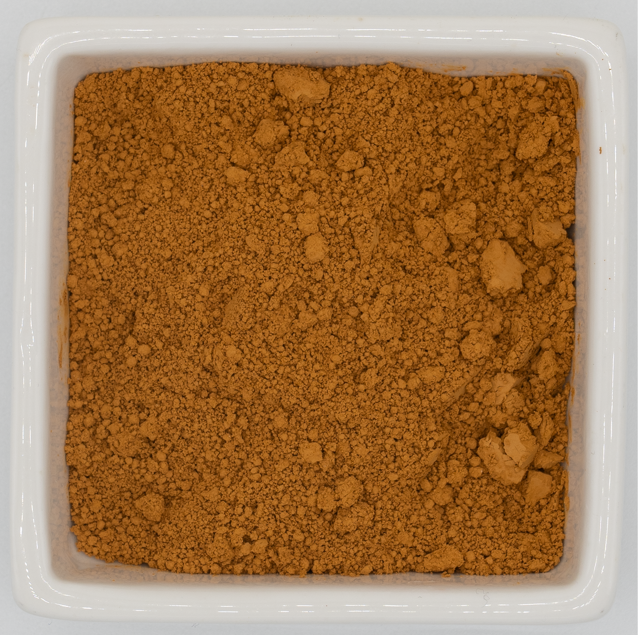 Orange earth in a square container on a light gray background