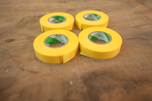 Four rolls of yellow tape on a wooden surface