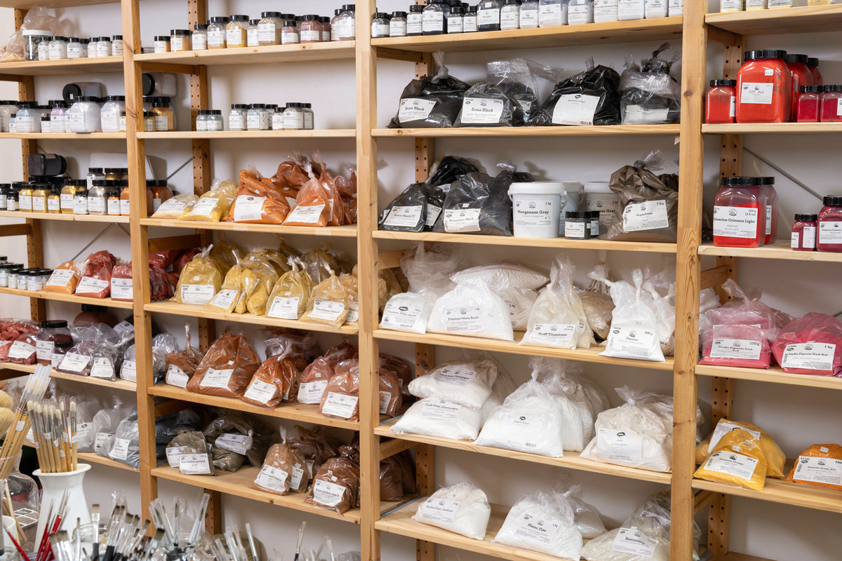 Wooden shelving stocked with packaged food items, jars, and bags of ingredients in a retail or kitchen supply setting.